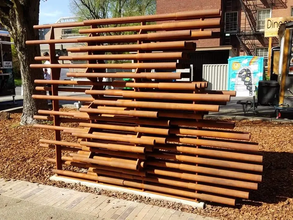 Anthropocene at Portland State University: horizontal rust-colored steel pipes form a cyclist-shaped opening.