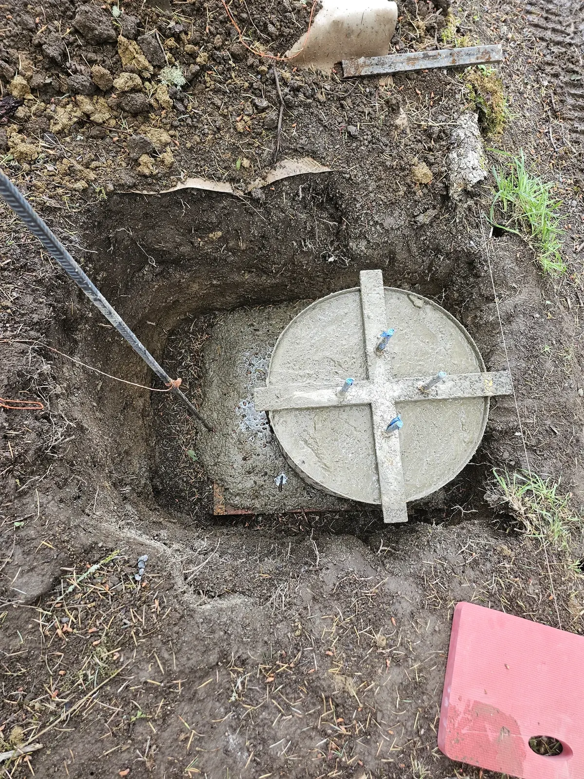 Overhead view of a circular concrete post footing with an anchor-bolt positioning template.