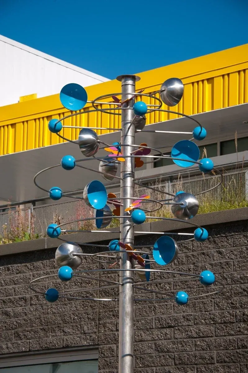 Carbon Atom Whirligig with stacked stainless steel hoops, blue spheres and blue wind-catching cups.