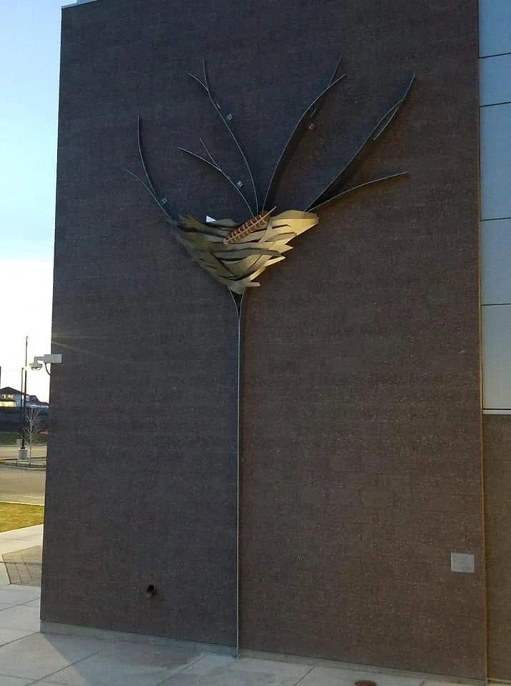 Front view of Fledge showing its long stem and upper metalwork against the exterior wall of Desert Hills Middle School.