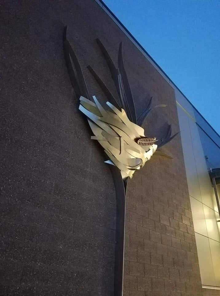Low-angle side view of Fledge showing the curved stainless steel center projecting from the school wall.