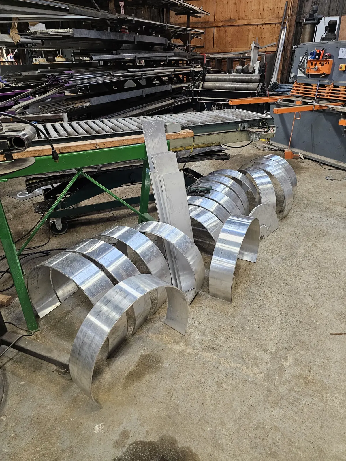Curved aluminum housing sections arranged on the shop floor.