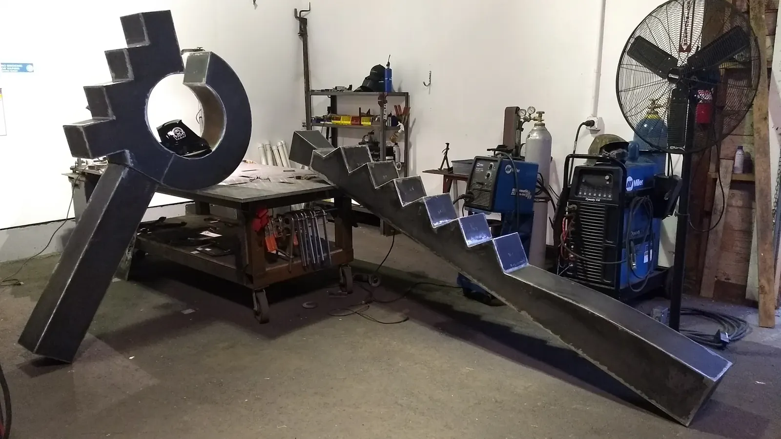 The circular form and long stepped column during fabrication, supported beside a workbench in the WIW shop.