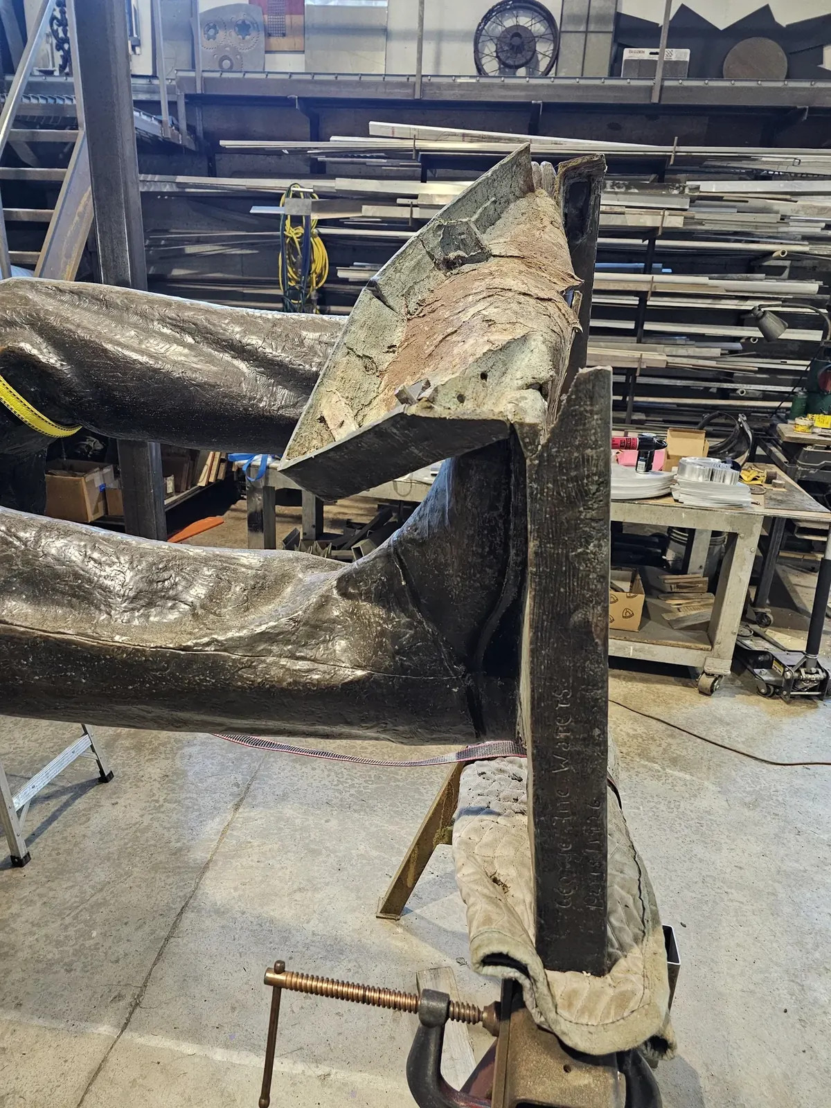Side view of Lincoln’s feet and the severely bent original bronze base in the shop.