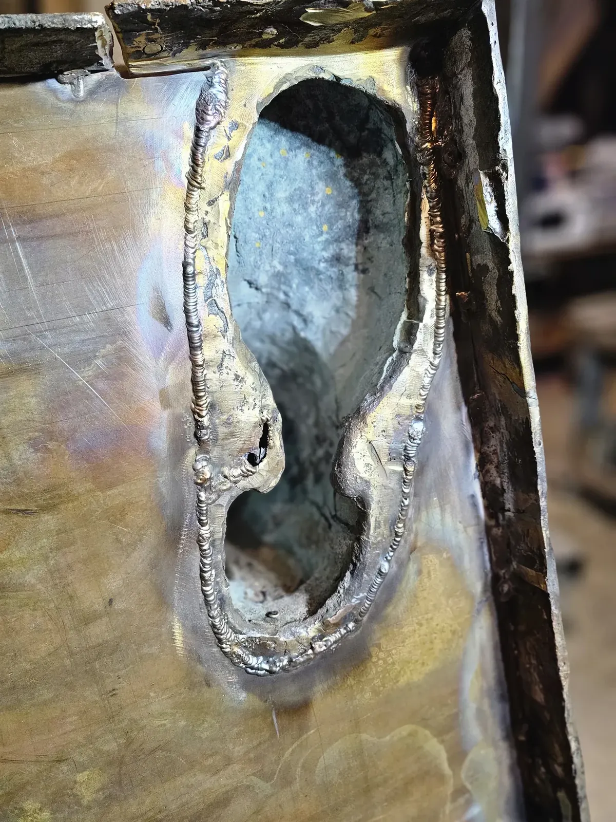 Detailed view of welds joining the preserved bronze around a foot opening to the new plate.