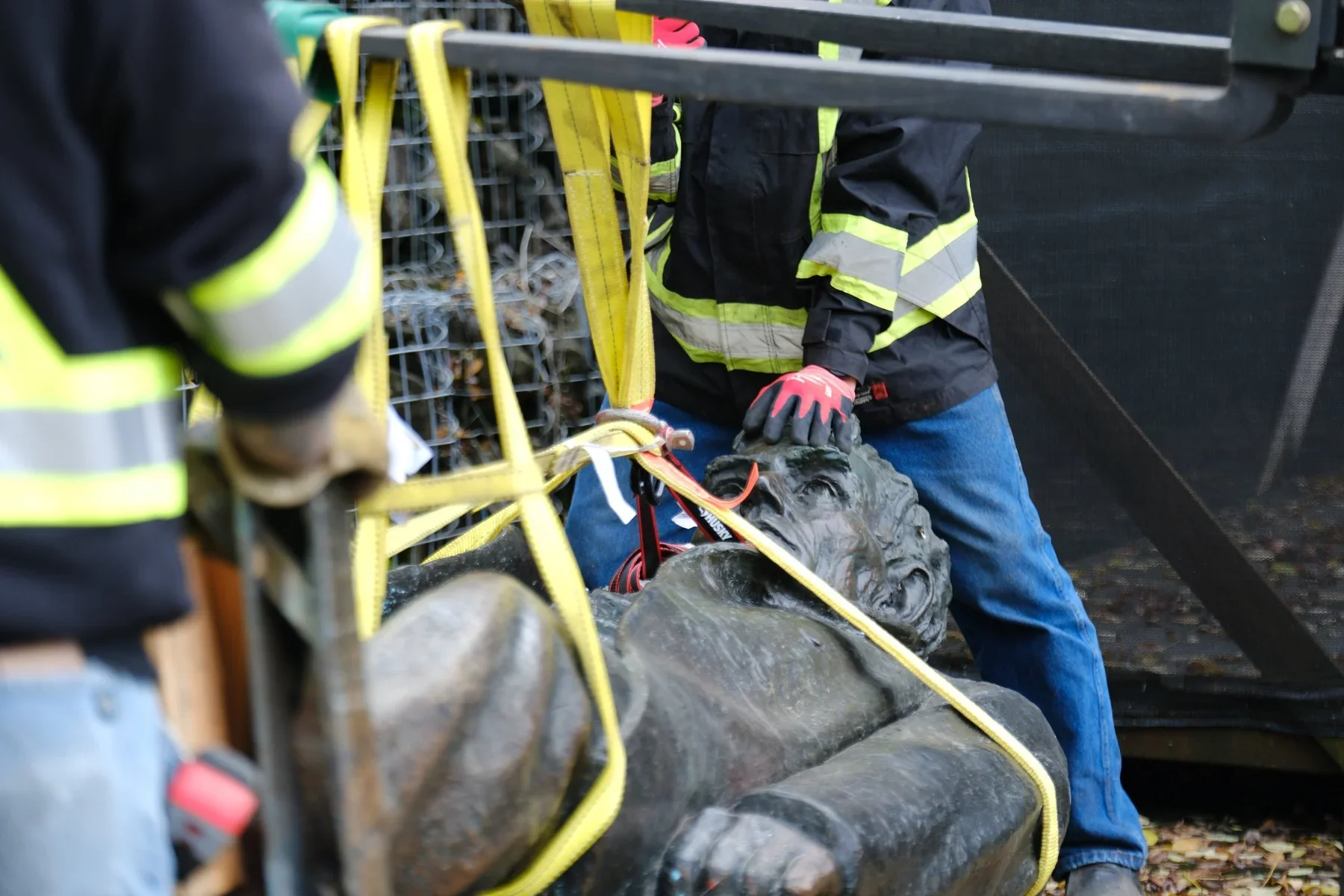 Workers in high-visibility jackets and yellow lifting straps around the reclining Lincoln statue.
