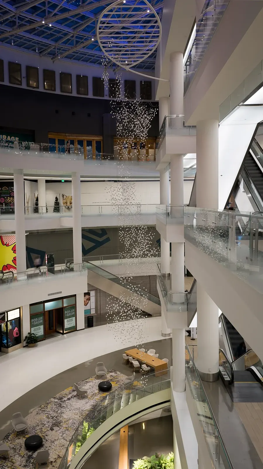 Murmuration suspended through the four-story Pacific Place atrium, with the overhead support frame visible above the sculpture.