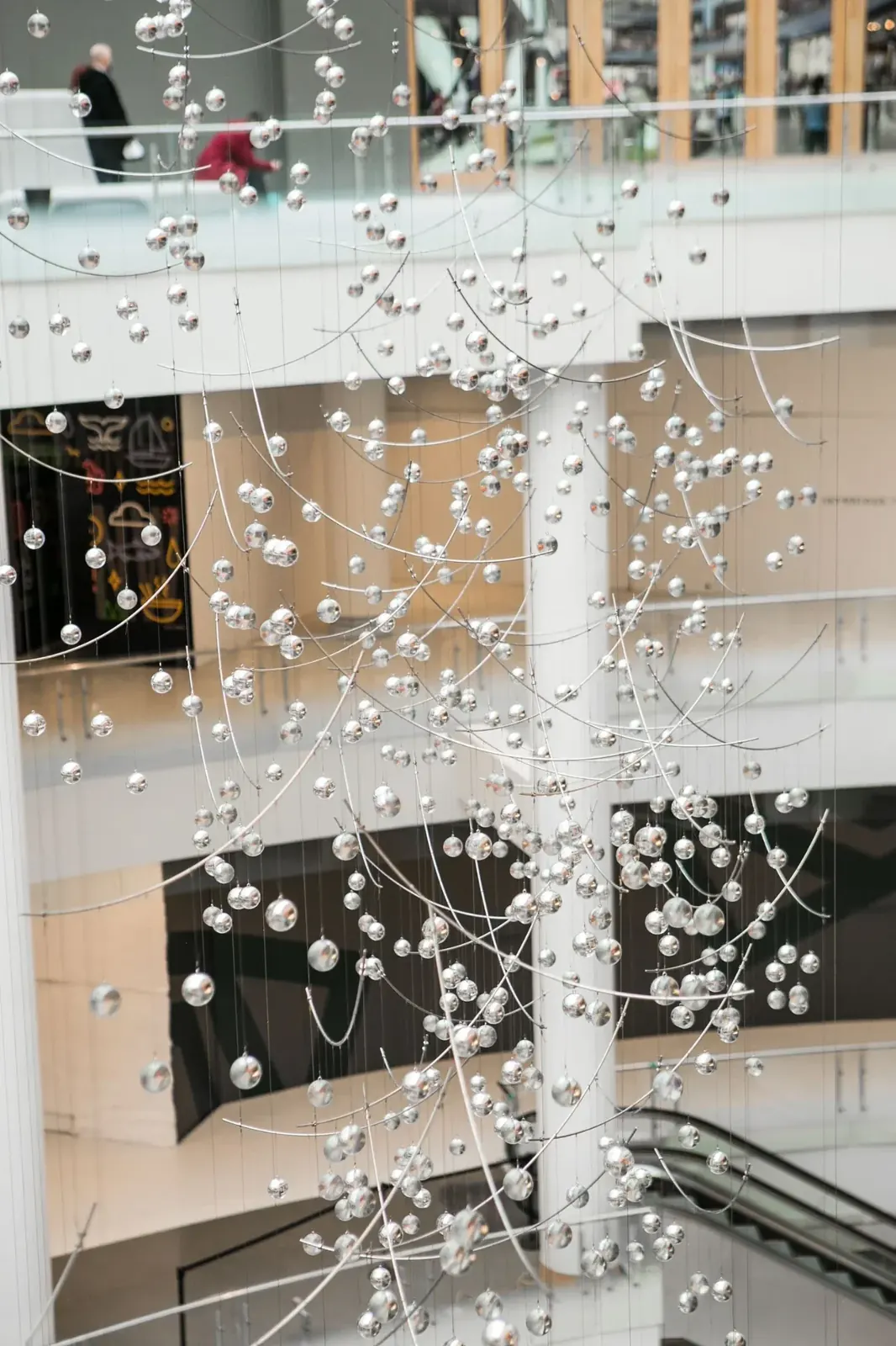 Reflective acrylic spheres arranged along curved rods, with slender suspension cables extending overhead.