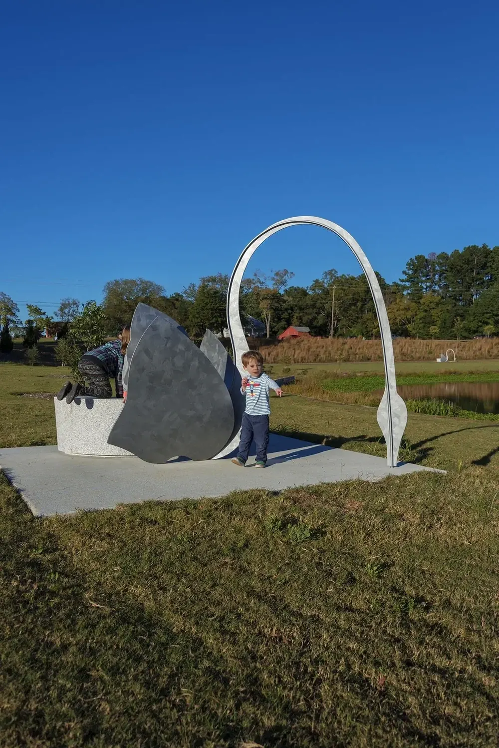 Children beside one of the swan sculptures and its granite bench, showing the scale of the artwork in the park.