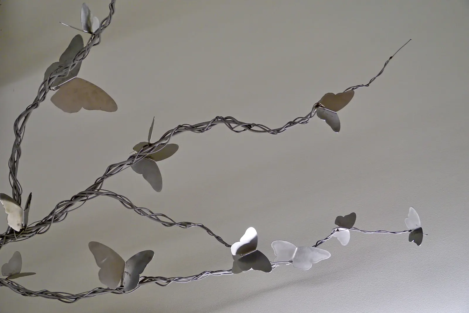 Close-up of individual stainless steel butterfly wings and the clustered metal strands forming the branches.