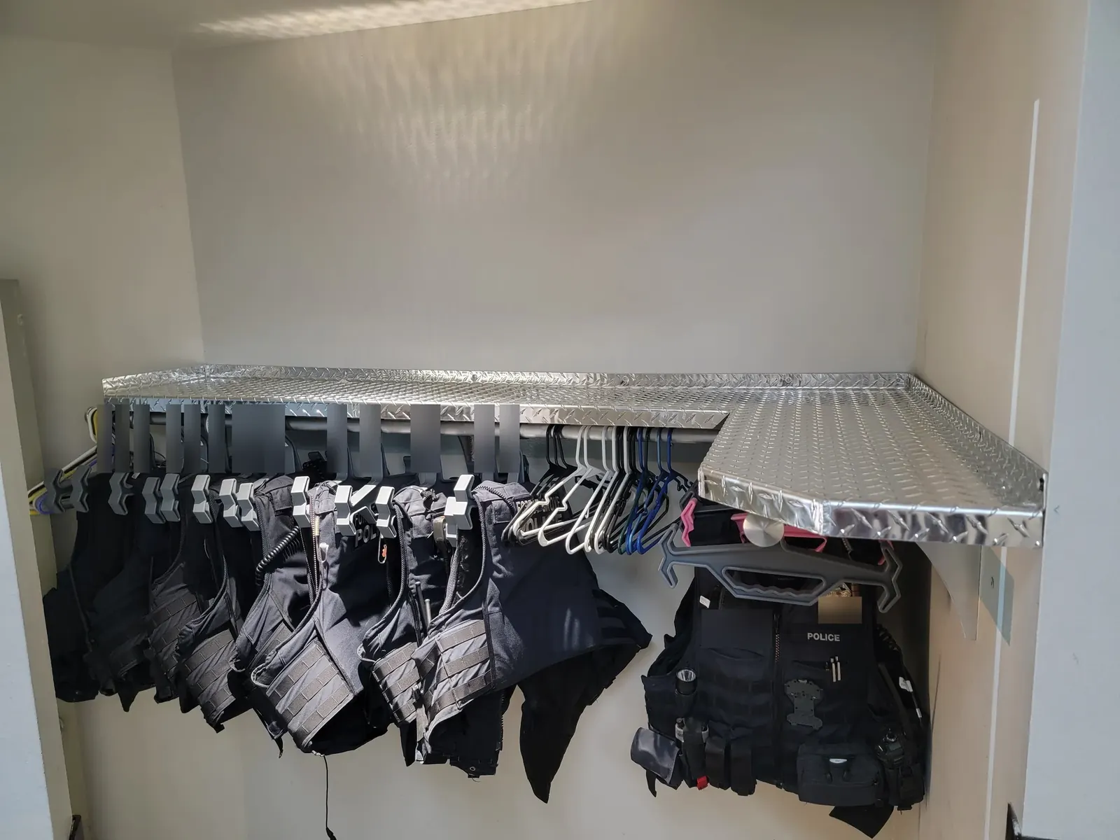 Diamond-plate corner shelves above a row of hanging ballistic vests