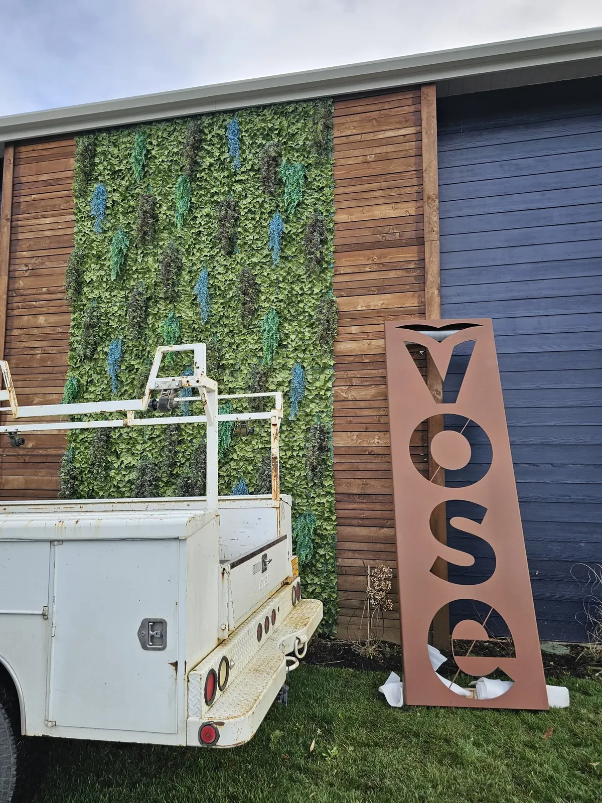 Tall rectangular metal panel with large cut-out Vose letters outside a building