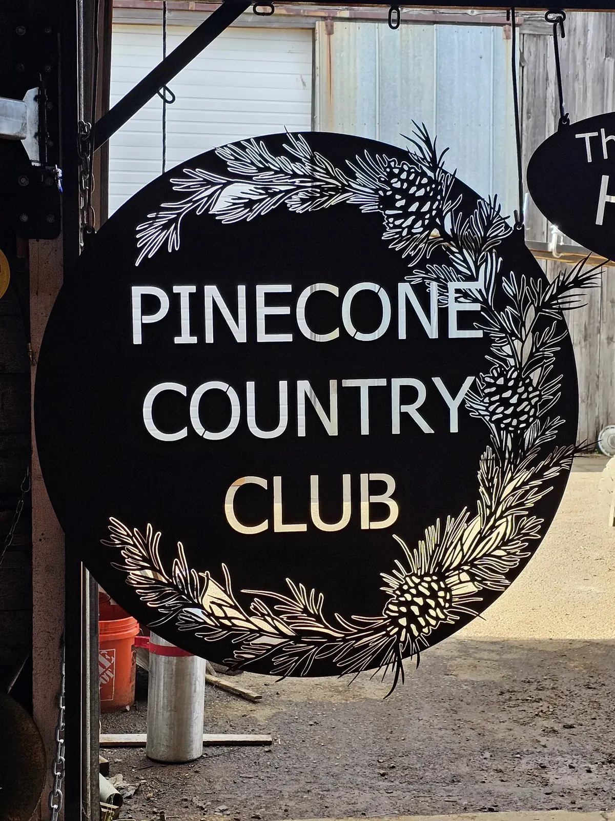 Round Pinecone Country Club sign with cut lettering and pinecones around the edge