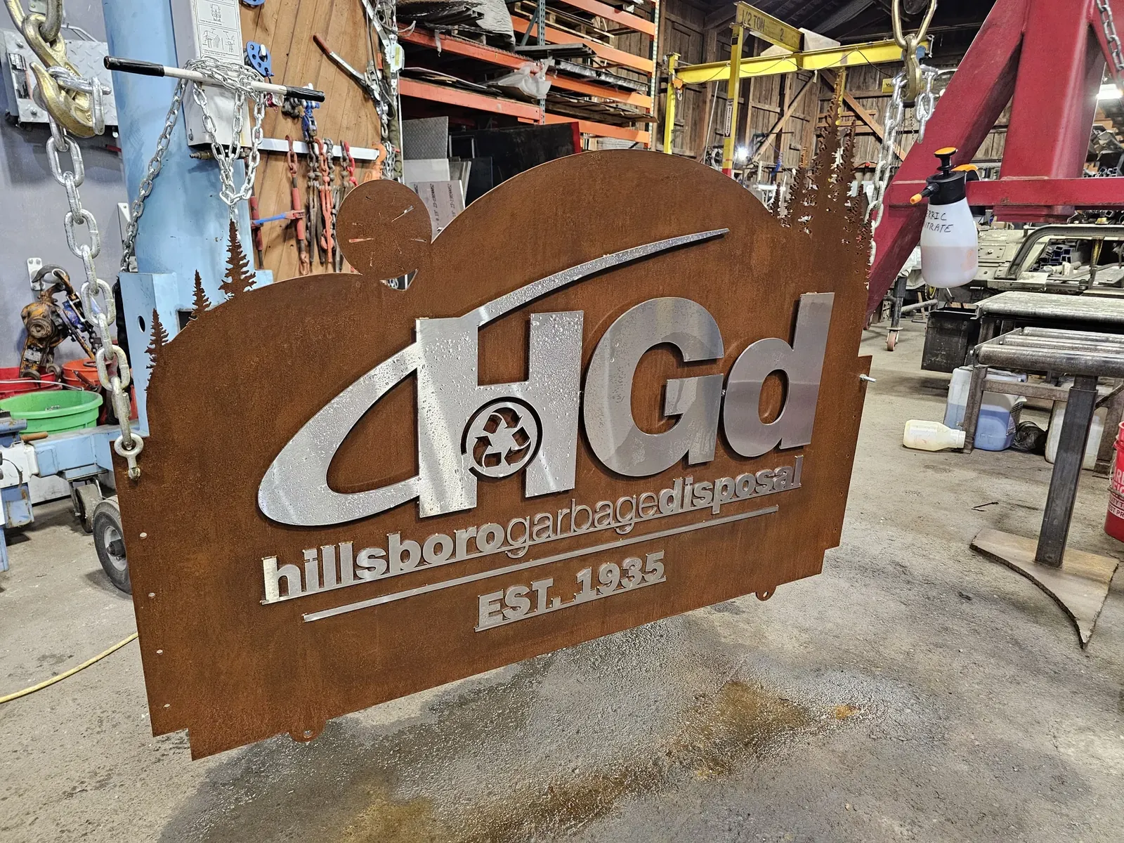 Hillsboro Garbage Disposal sign with bright raised lettering and a tree-line silhouette