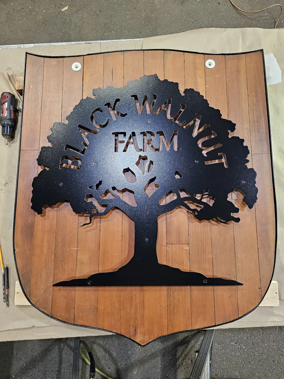 Black Walnut Farm sign with a dark metal tree silhouette and lettering over wood
