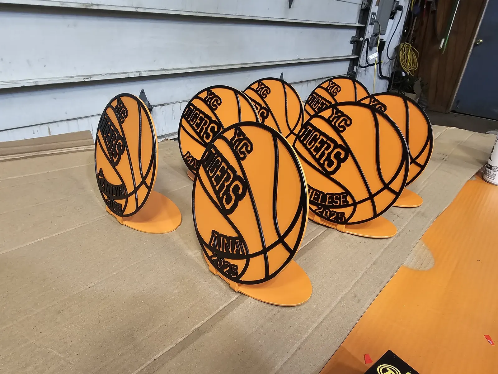 A group of orange and dark metal Tigers basketball awards with individual names