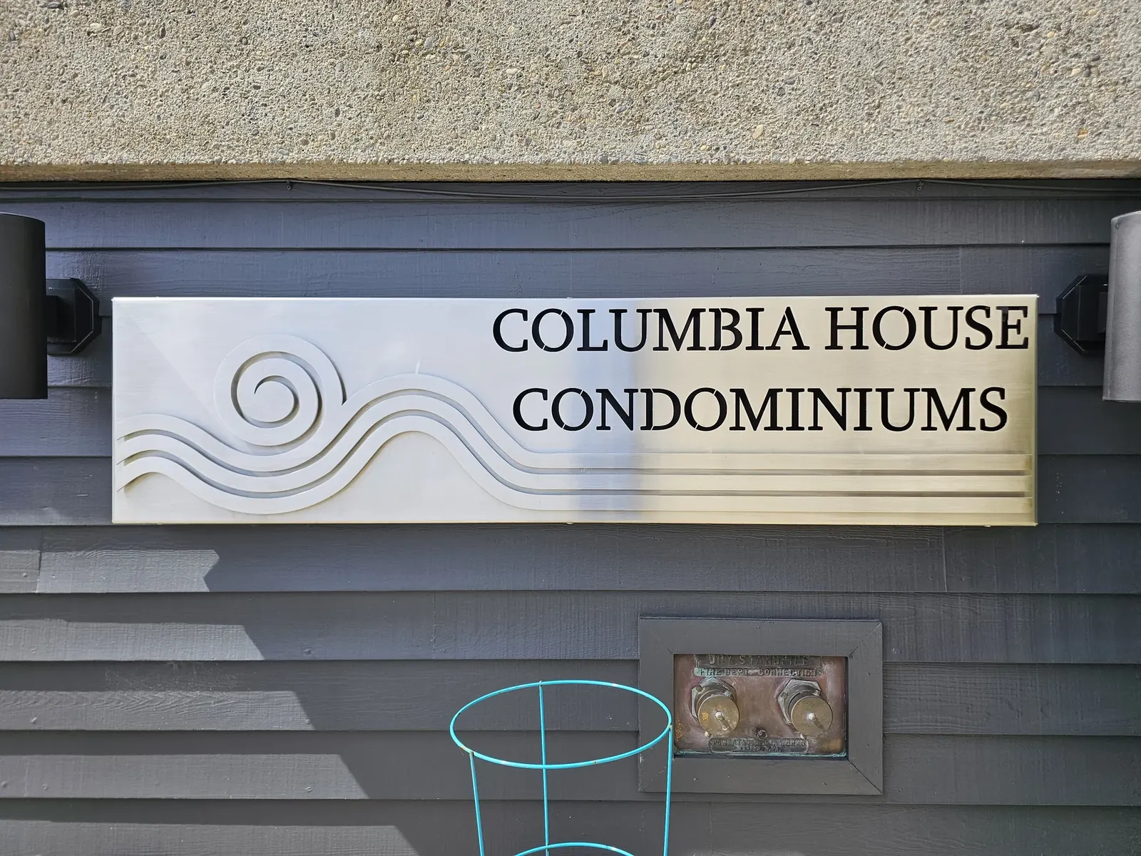 Columbia House Condominiums lettering above layered metal waves on a wall