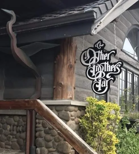 Shaped Other Brothers Bar sign with contrasting script lettering hanging outside the building