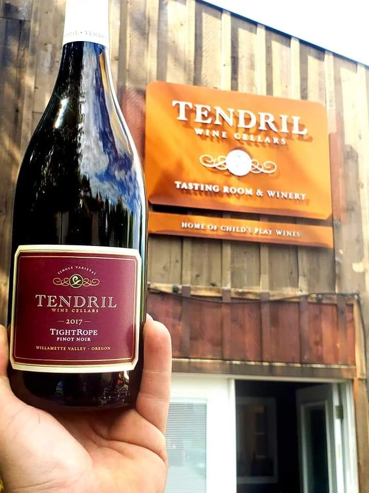 Tendril Wine Cellars sign on a wood building, with a wine bottle in the foreground