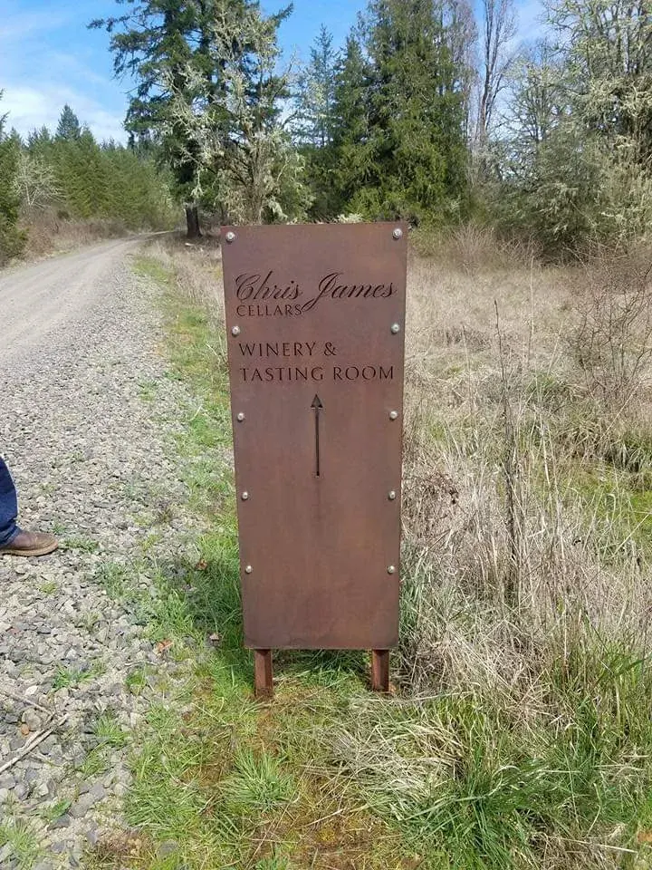 Tall Chris James Cellars metal sign with an upward arrow for the winery and tasting room