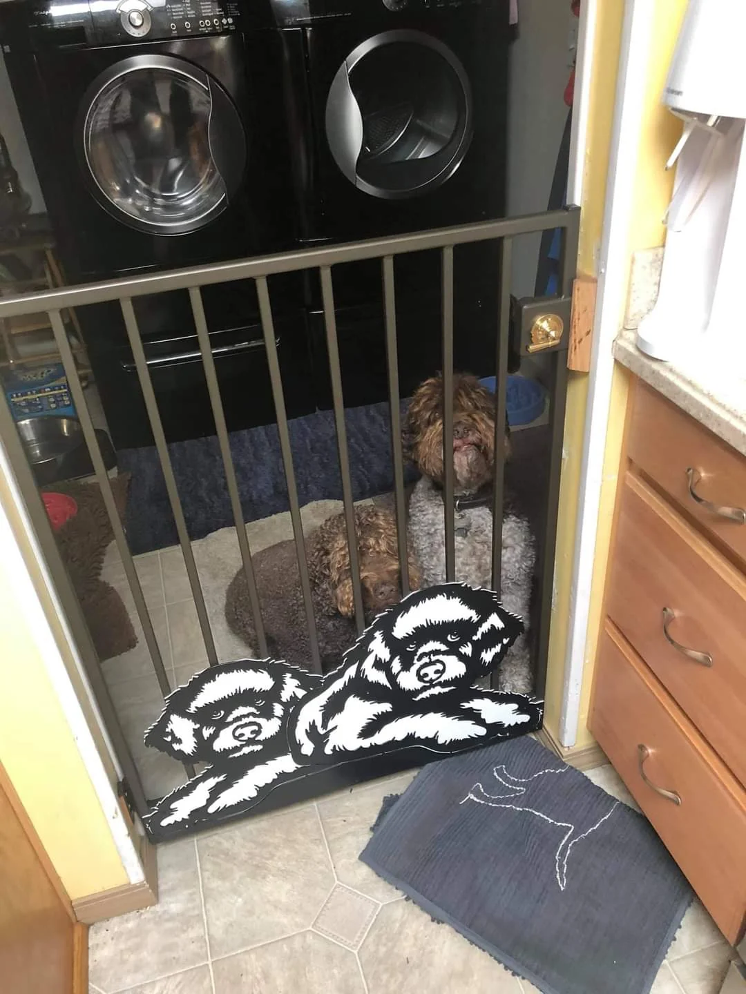 Indoor metal gate with vertical bars and a dog portrait panel, with a dog behind the gate