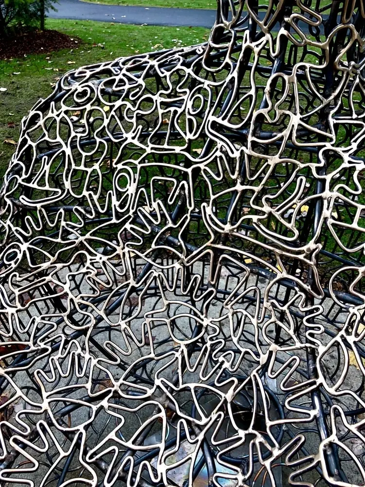 Bronze outlines of people, hands, houses and bicycles across the seat of a Community figure.
