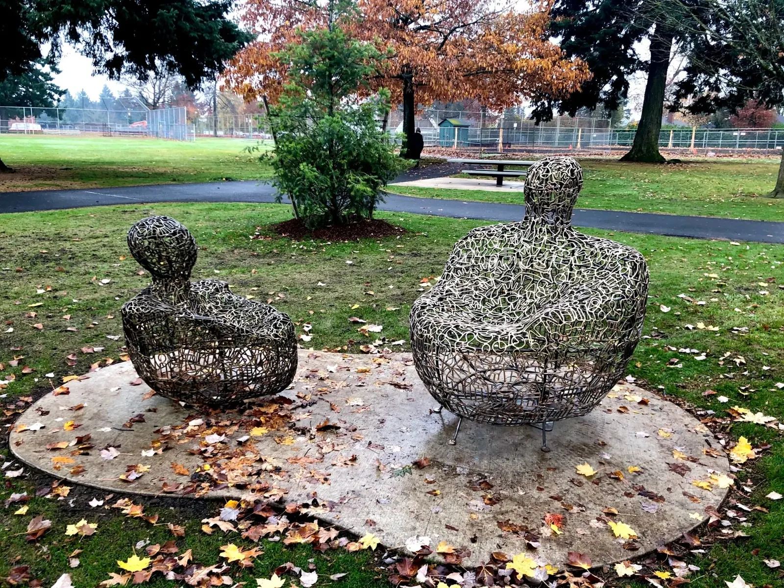 Two bronze seats shaped as an adult and child, with open contour patterns, at Glenhaven Park.