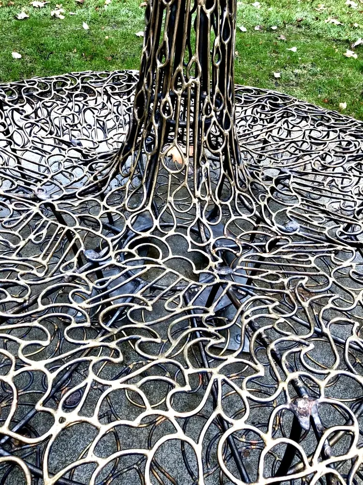 Curving bronze outlines of clouds, waves and droplets across the base and stem of Water.