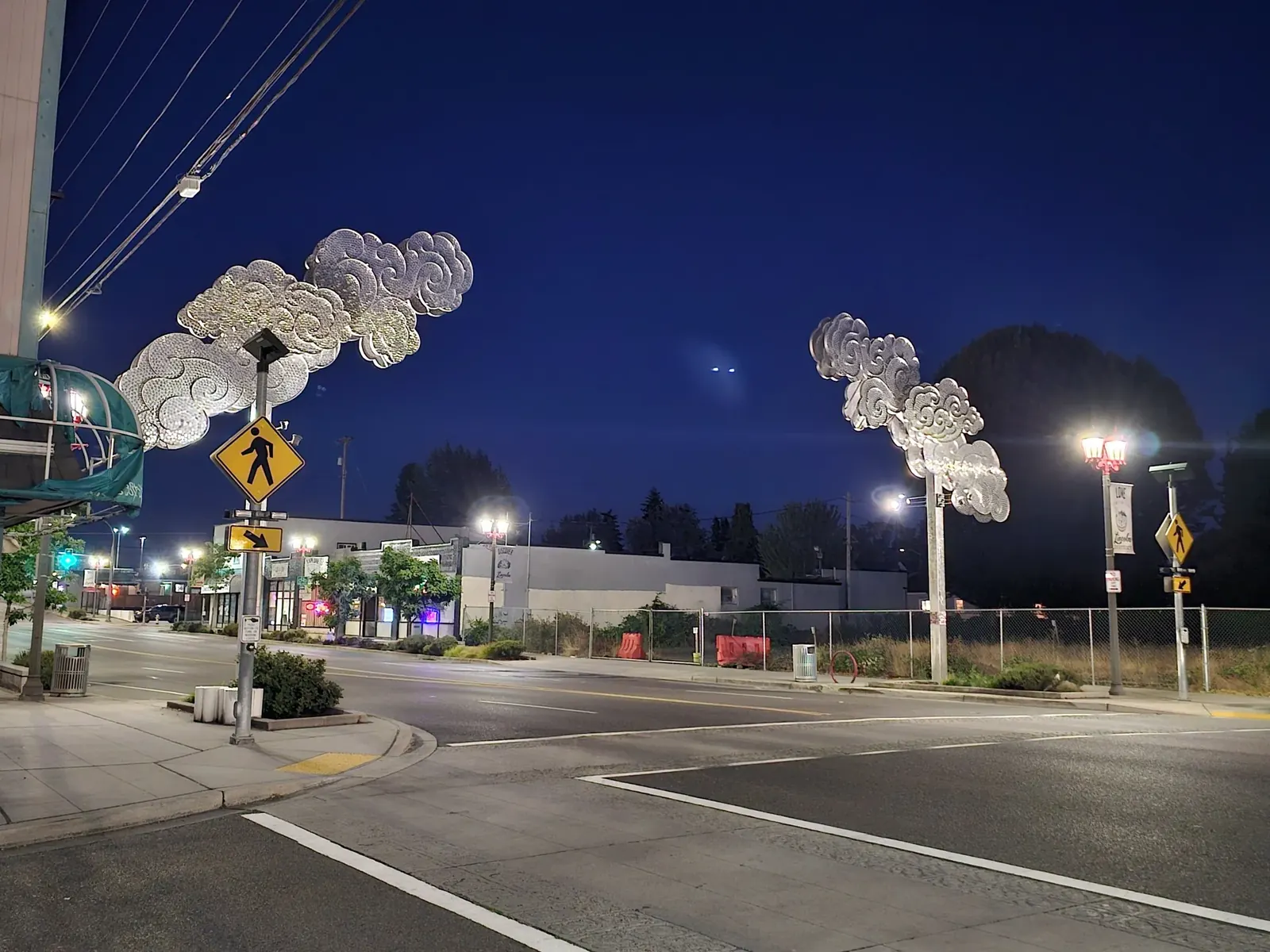 Two illuminated metal cloud gateways above the street at night in Tacoma.