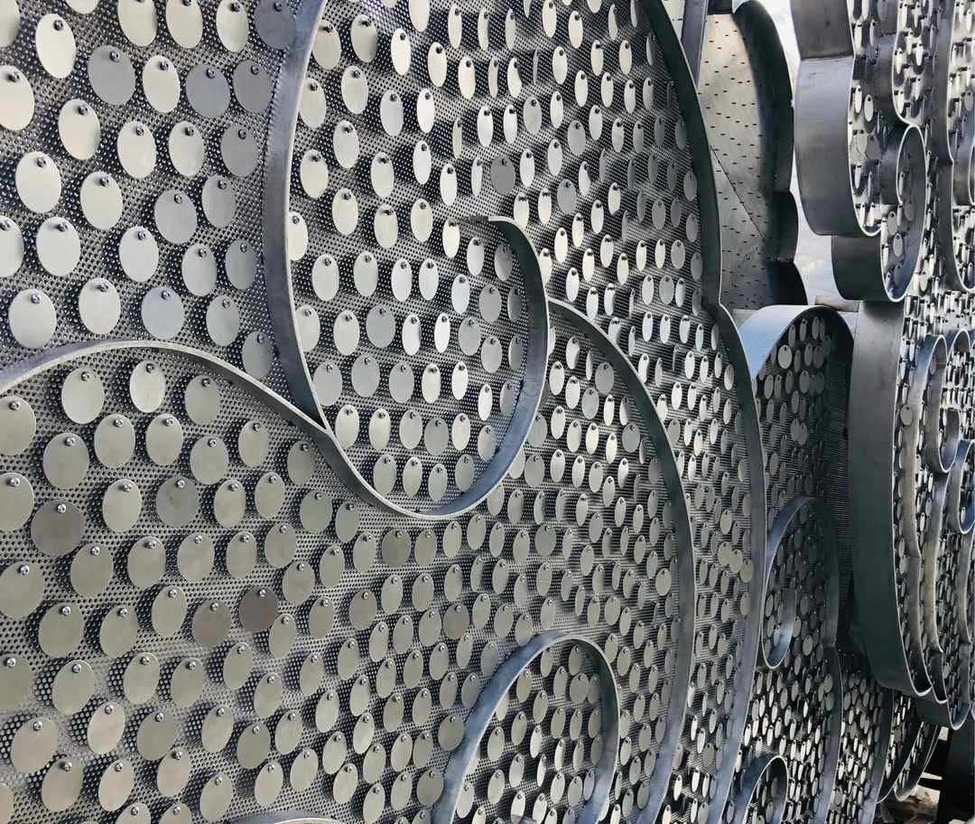 Close-up of round stainless steel discs attached at their top edges to the patterned cloud structure, with curved metal outlines in front.