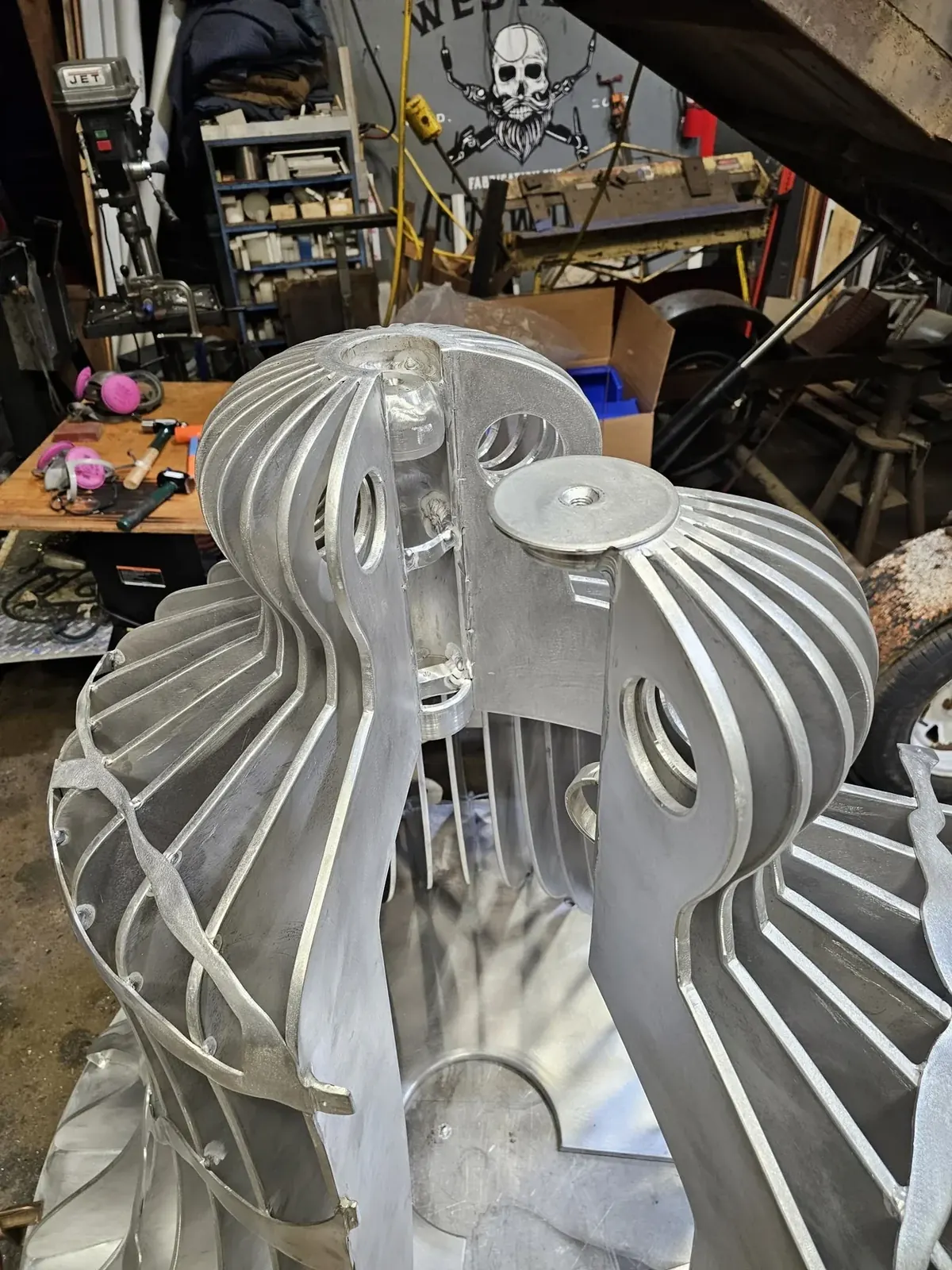 Open sections of an aluminum bell reveal its interior, rounded fin tops, and circular plate details.