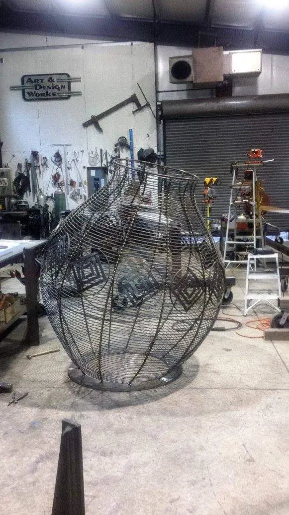 Rounded basket frame in the shop with geometric diamond motifs visible in the inner steelwork.